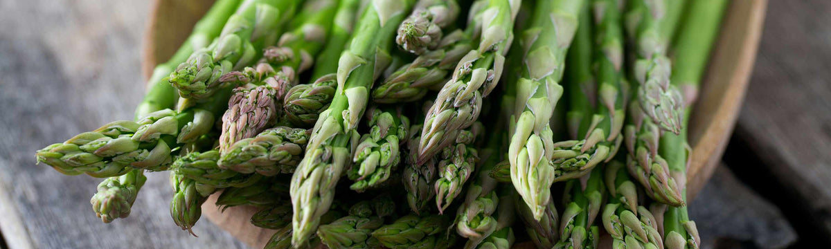 Freshly harvested green asparagus spears with tightly closed tips, showing the homegrown crop produced from asparagus crowns.